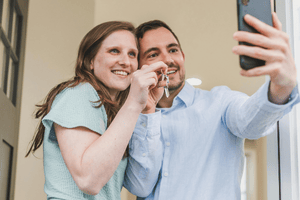 a couple takes a selfie holding up the keys to their new home