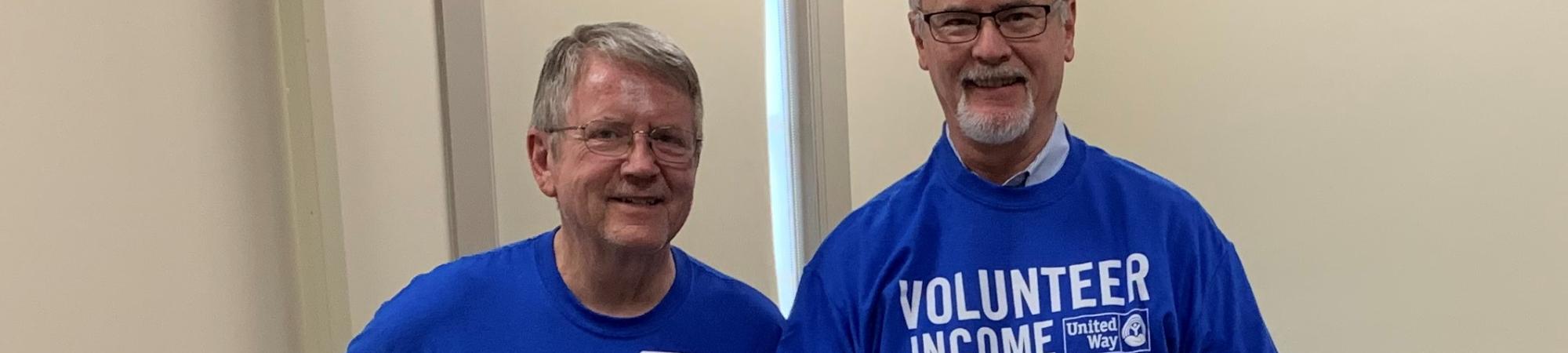Two male tax volunteers pose in VITA tshirts