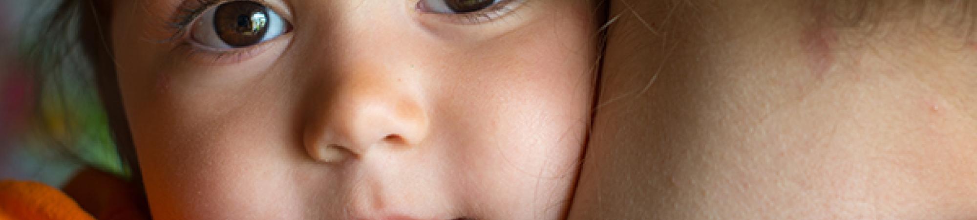 child looking over mothers shoulder