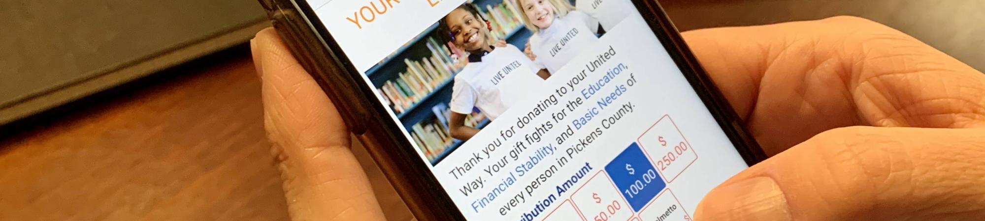 Person holding a phone opened to the donation page