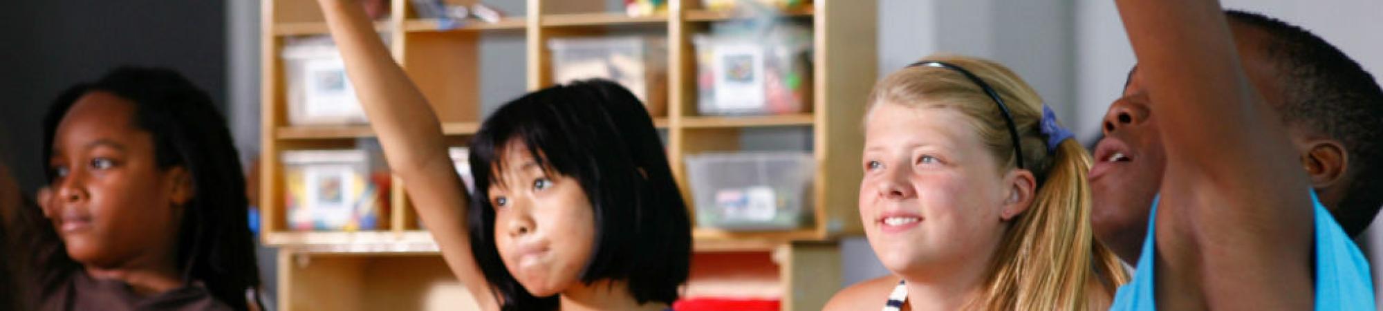 children in a classroom raising hands