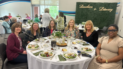 women smiling at the camera and sitting at the table at the Luncheon for Literacy